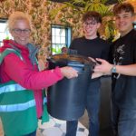 A volunteer collecting a tub of coffee from two of the Koffee staff